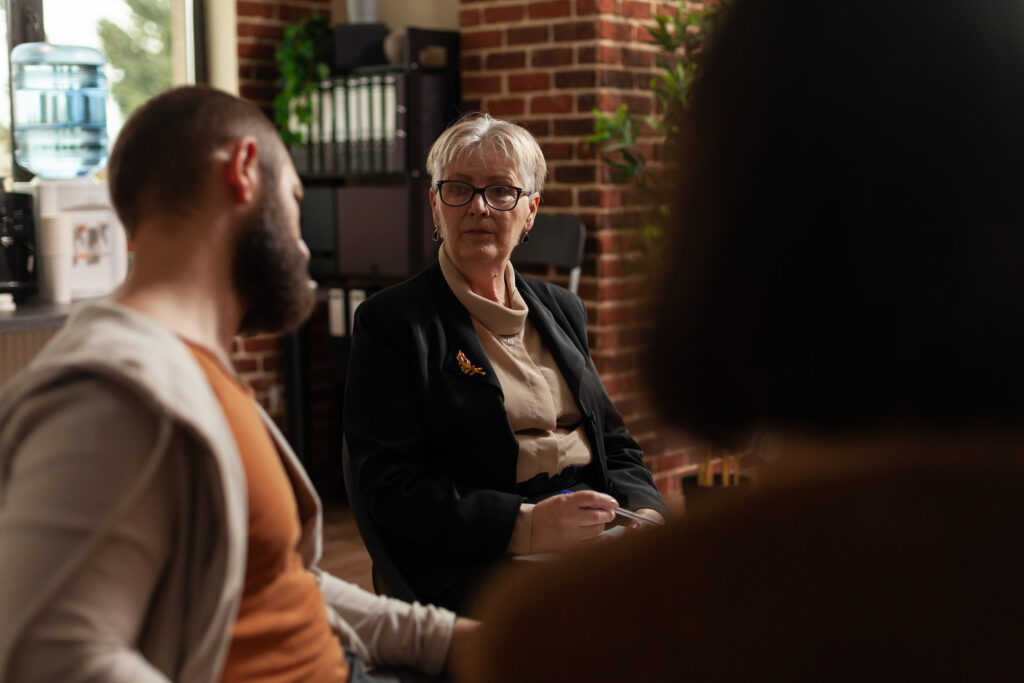 close up of psychologist having discussion with alcoholic people at aa meeting